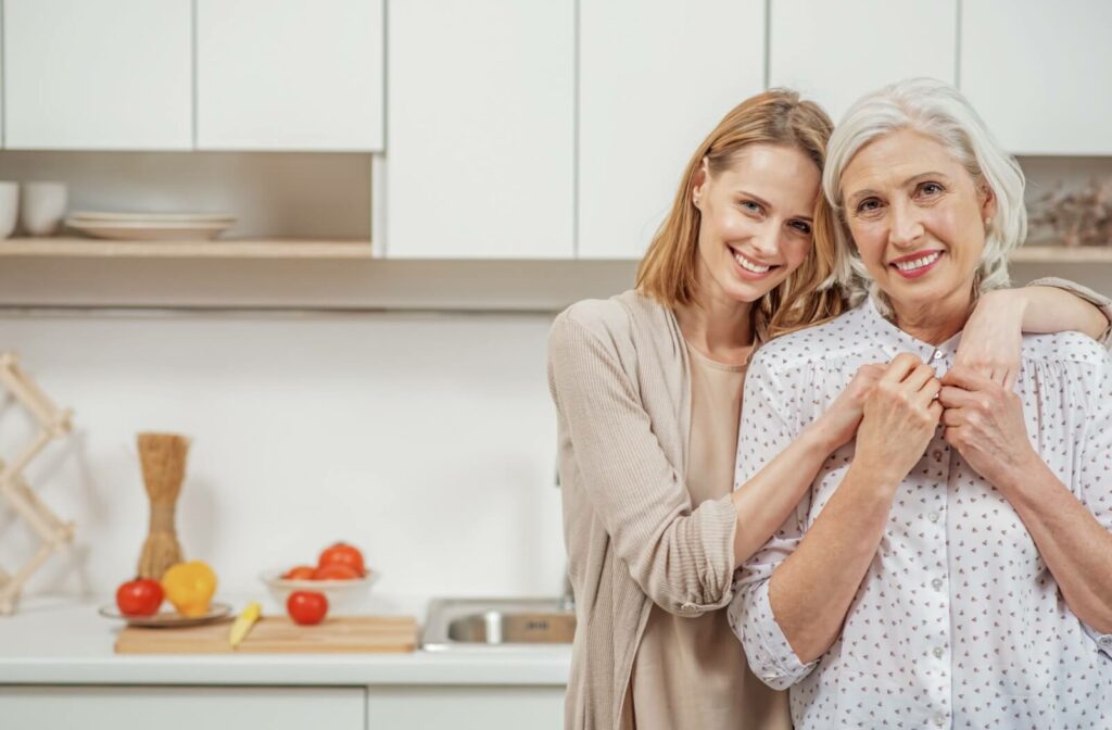 a woman and her senior parent hugging in a kitchen