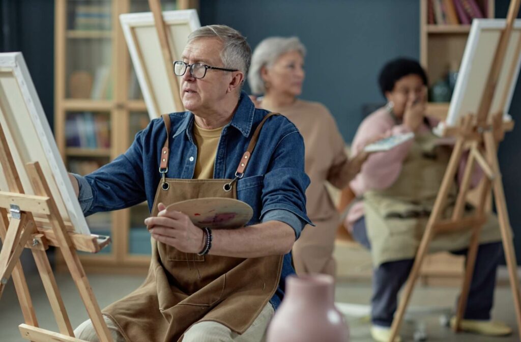 An individual attempts their hand at painting during a class at an assisted living community